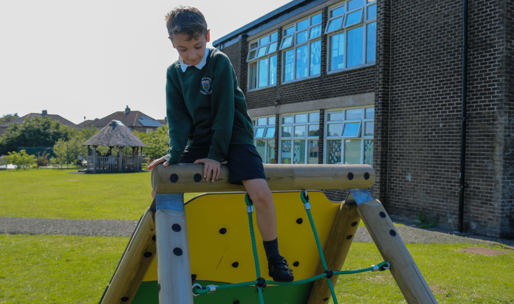 school child climbing on playground equipment 